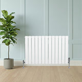 Witte designradiator met vlakke panelen en haakse thermostaatkraan, geplaatst tegen een lichte wand, naast een groene plant