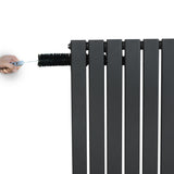 Vlakke panelen design radiator in antraciet grijs, met hand die een haakse thermostaatkraan aanraakt voor eenvoudige bediening
