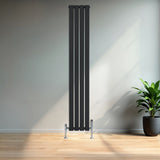 Zwarte designradiator met vlakke panelen en haakse thermostaatkraan, geplaatst in een moderne ruimte met houten vloer en groene plant