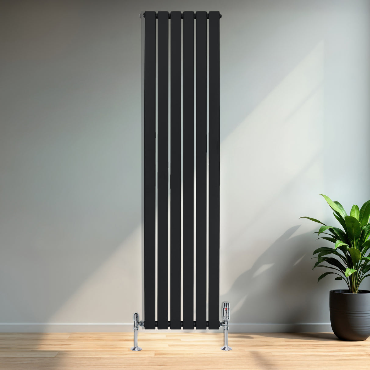 Zwarte designradiator met vlakke panelen en haakse thermostaatkraan, geplaatst tegen een lichte muur in een moderne ruimte