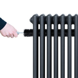 Traditionele antraciet grijze 4-kolom radiator met hand die een borstel gebruikt voor onderhoud en reiniging