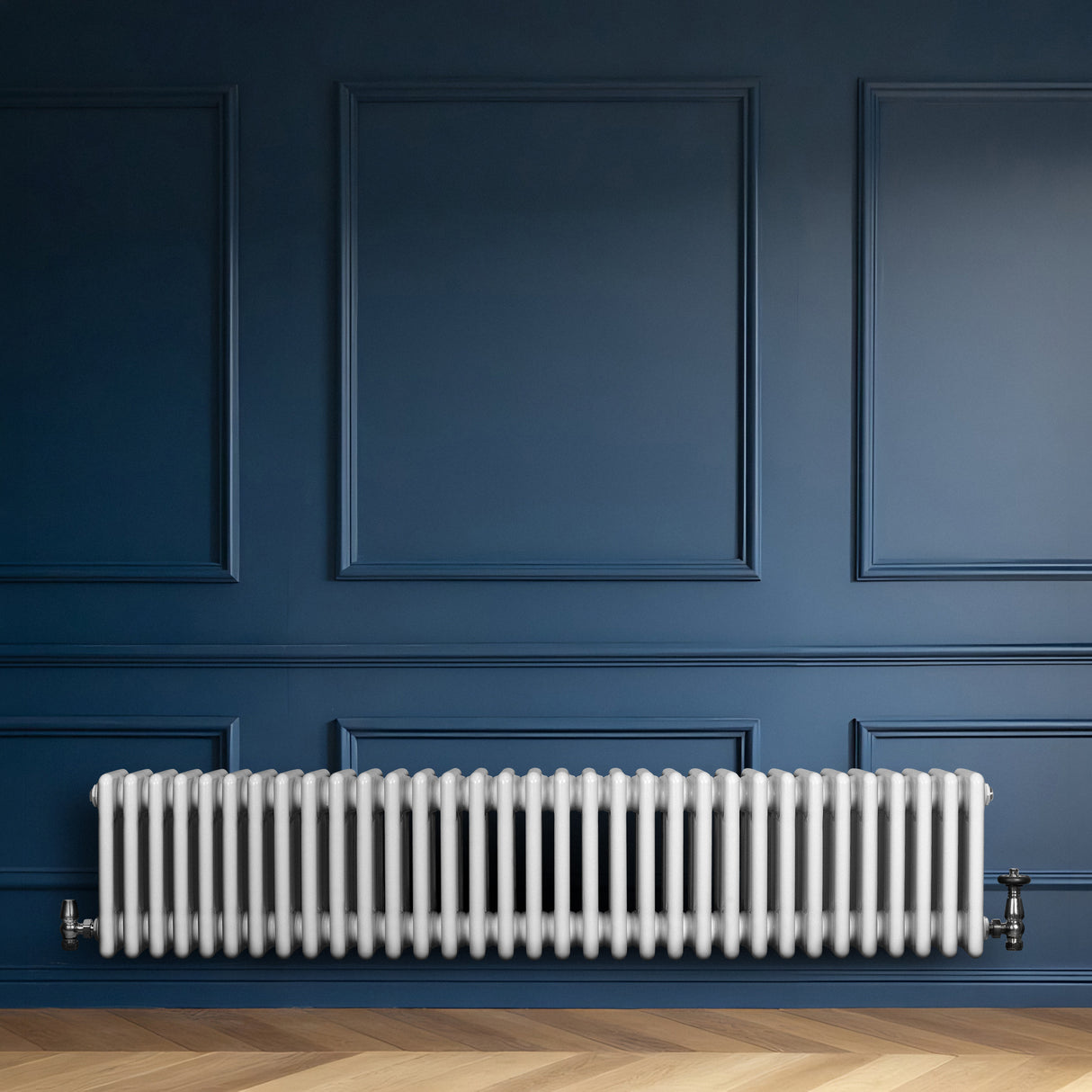Traditionele witte 4-kolom radiator van 300 x 1505 mm met haakse thermostaatkraan, geplaatst tegen een donkerblauwe muur