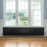 Traditionele zwarte 4-kolom radiator van 300 x 1505 mm met een haakse thermostaatkraan, geplaatst onder een groot raam
