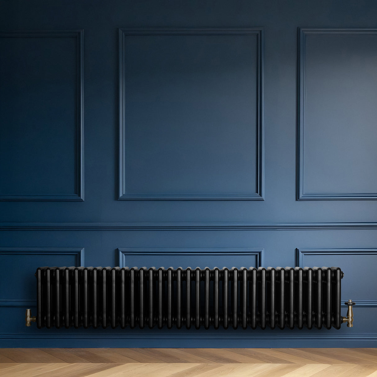 Traditionele zwarte 4-kolom radiator van 300 x 1505 mm met haakse thermostaatkraan, geplaatst tegen een blauw paneelwand