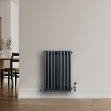 Traditionele antraciet grijze 4-kolom radiator van 600 x 425 mm met haakse thermostaatkraan, strak tegen een muur geplaatst