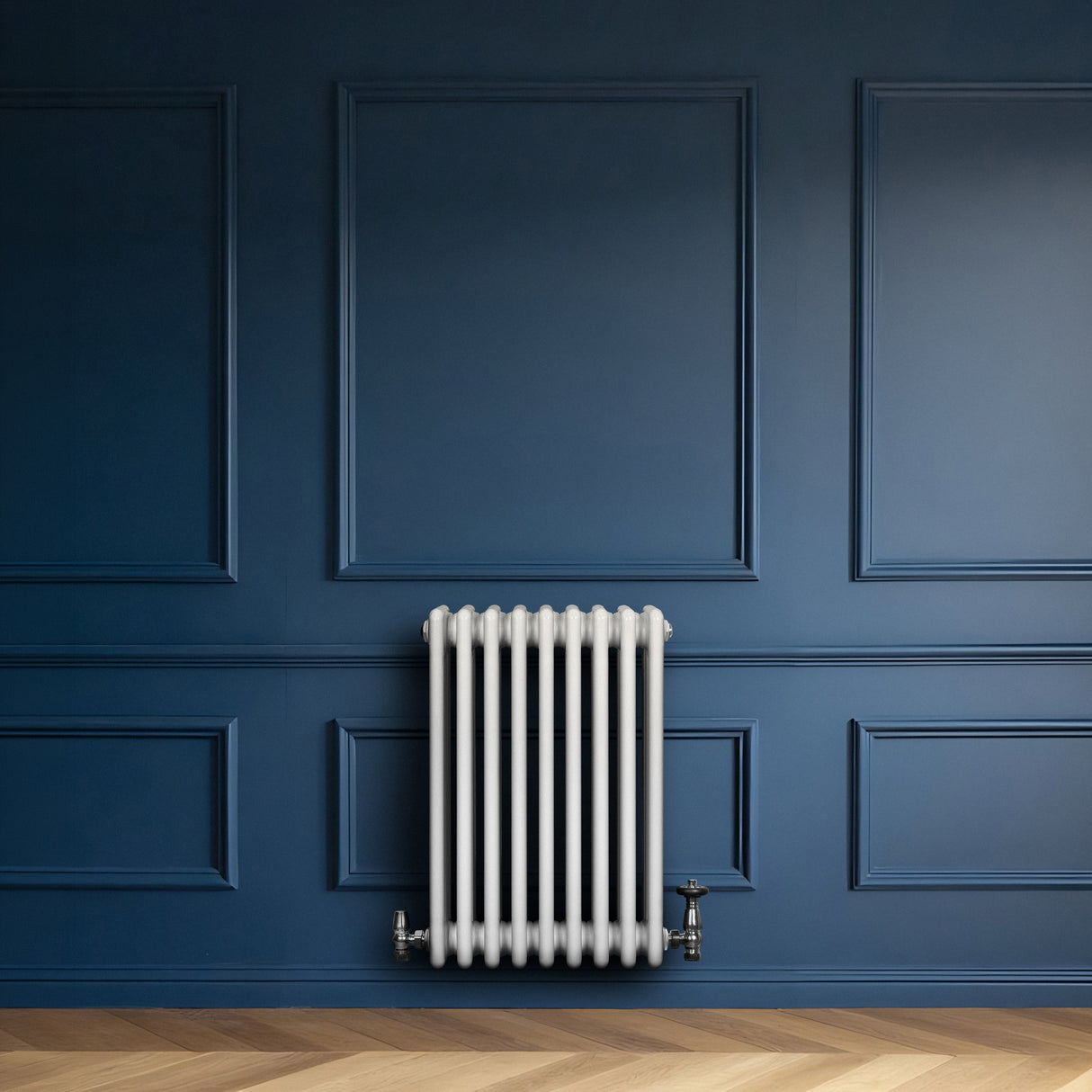 Traditionele witte 4-kolom radiator van 600 x 425 mm met haakse thermostaatkraan tegen een donkerblauwe wand
