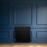 Traditionele zwarte 4-kolom radiator van 600 x 605 mm met haakse thermostaatkraan, geplaatst tegen een diepblauwe muur