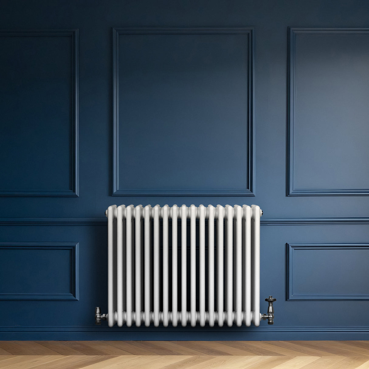 Traditionele witte 4-kolom radiator van 600 x 785 mm met haakse thermostaatkraan, geplaatst tegen een donkerblauwe muur