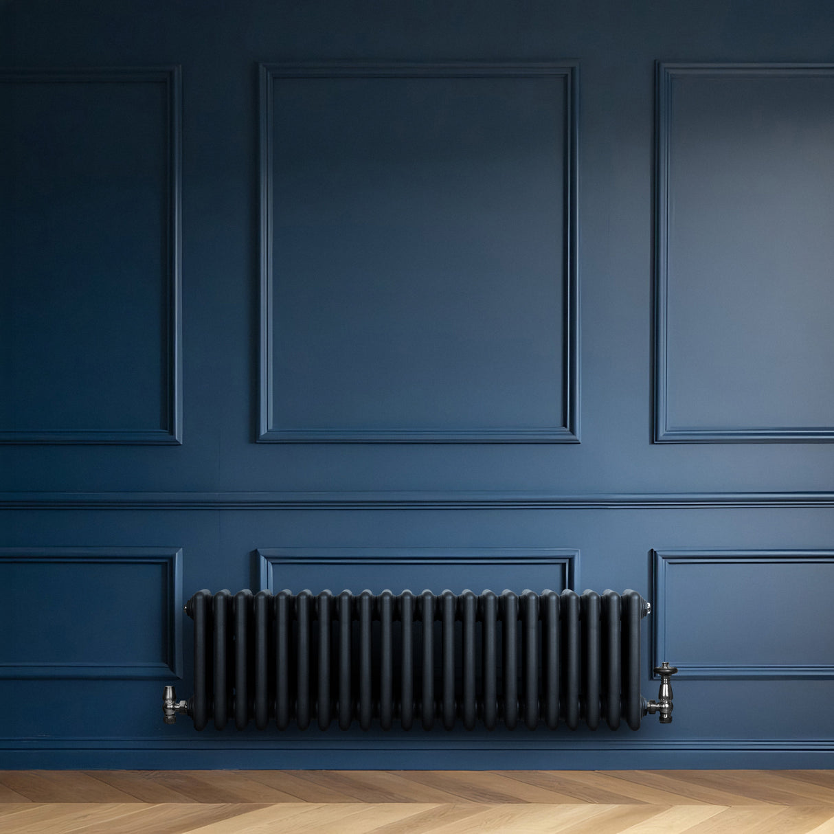 Traditionele 4-kolom radiator in antraciet grijs, geplaatst tegen een diepblauwe wand, met een strakke, moderne uitstraling