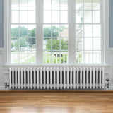 Traditionele witte 4-kolom radiator van 300 x 1370 mm, met een glanzende afwerking en een elegant, retro ontwerp in een lichte kamer