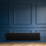 Traditionele zwarte 4-kolom radiator van 300 x 1370 mm, geplaatst tegen een diepblauwe wand met een elegante afwerking