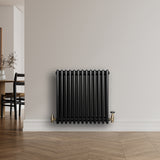 Traditionele zwarte 4-kolom radiator van 600 x 605 mm met glanzende afwerking, geplaatst tegen een lichte muur in een moderne ruimte