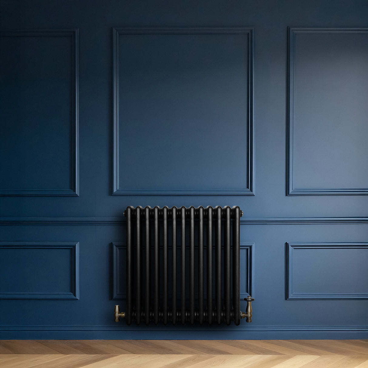 Traditionele zwarte 4-kolom radiator van 600 x 605 mm tegen een diepblauwe wand, met een elegante, glanzende afwerking en gouden kranen