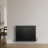 Traditionele zwarte 4-kolom radiator van 600 x 785 mm met een glanzende afwerking, geplaatst tegen een lichte muur in een moderne ruimte