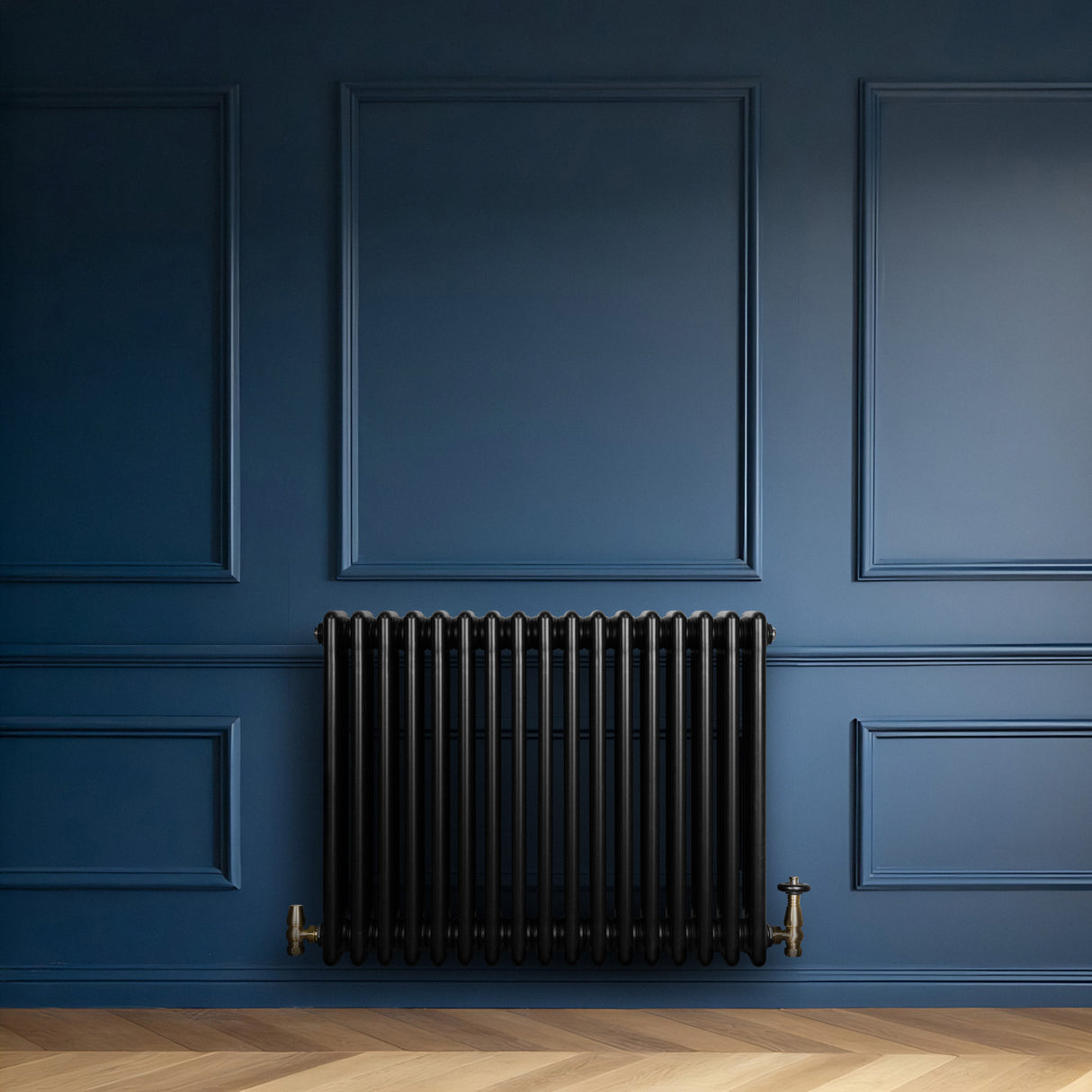 Traditionele zwarte 4-kolom radiator van 600 x 785 mm tegen een diepblauwe muur, met een glanzende afwerking en gouden kranen