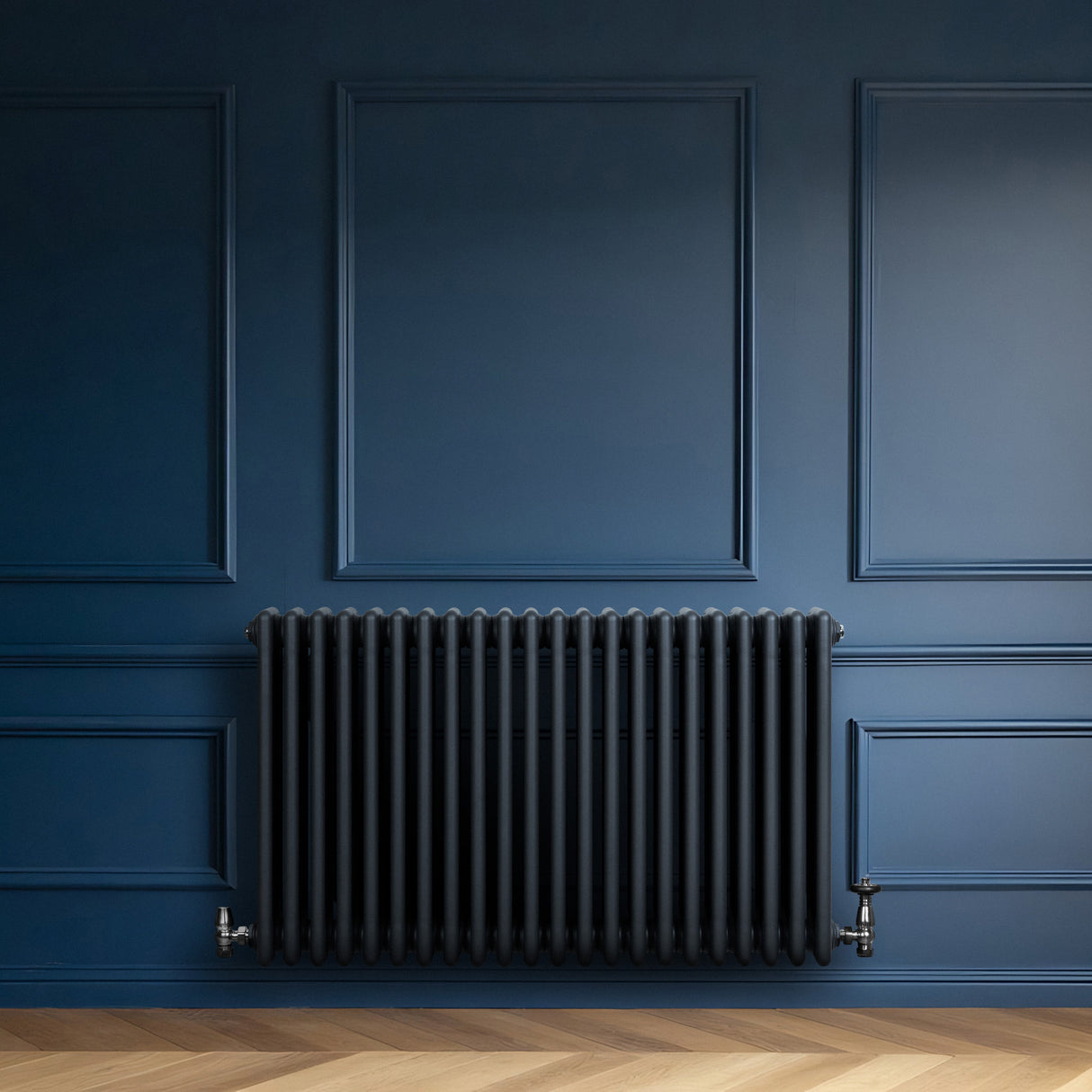 Traditionele 4-kolom radiator in antracietgrijs, met een strakke, moderne afwerking tegen een diepblauwe muur