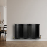 Traditionele zwarte 4-kolom radiator van 600 x 1010 mm met glanzende afwerking, geplaatst tegen een lichte muur in een moderne ruimte