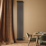 Traditionele 4-kolom radiator in antraciet grijs, verticaal gemonteerd aan een beige muur, met houten vloer en moderne meubels