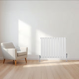 Witte design radiator met vlakke panelen en één kolom, geplaatst in een lichte ruimte met een moderne stoel en houten vloer