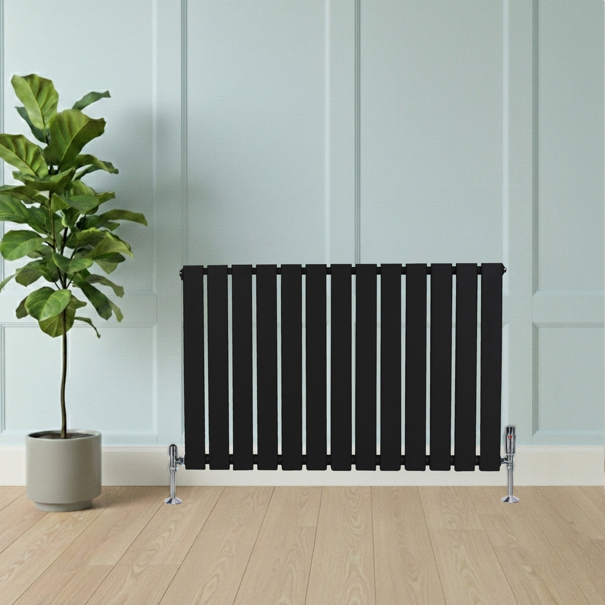 Zwart designradiator met vlakke panelen en één kolom, geplaatst tegen een lichte wand, naast een groene plant in pot