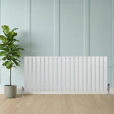 Witte designradiator met vlakke panelen, 1 kolom, 600 x 1400mm, geplaatst tegen een lichte wand met een groene plant ernaast