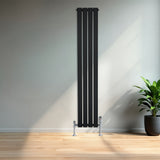 Zwarte designradiator met vlakke panelen, 1 kolom, 1600 x 280mm, geplaatst tegen een lichte muur met een groene plant ernaast