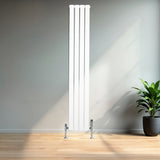 Strakke, witte design radiator met vlakke panelen en één kolom, geplaatst in een lichte ruimte met houten vloer en een groene plant
