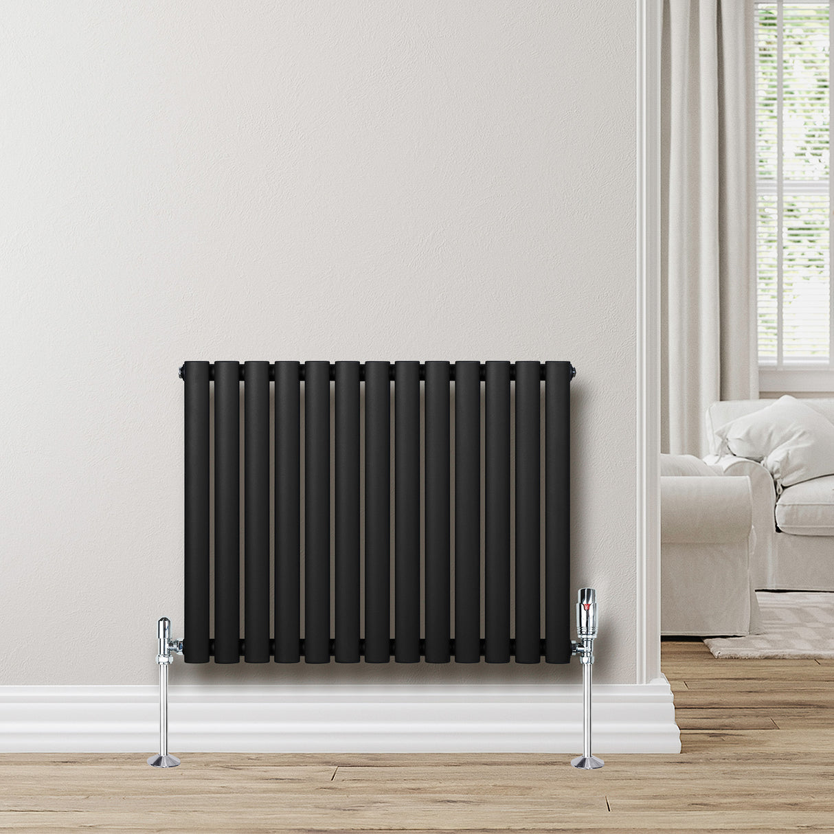 Ovale zwarte design radiator met één kolom, 600 mm x 780 mm, geplaatst tegen een lichte muur in een moderne woonkamer