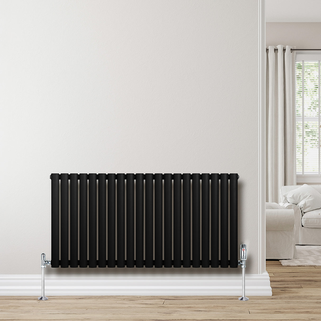 Ovale zwarte designradiator met één kolom, 600 mm x 1200 mm, geplaatst tegen een lichte muur in een moderne woonkamer
