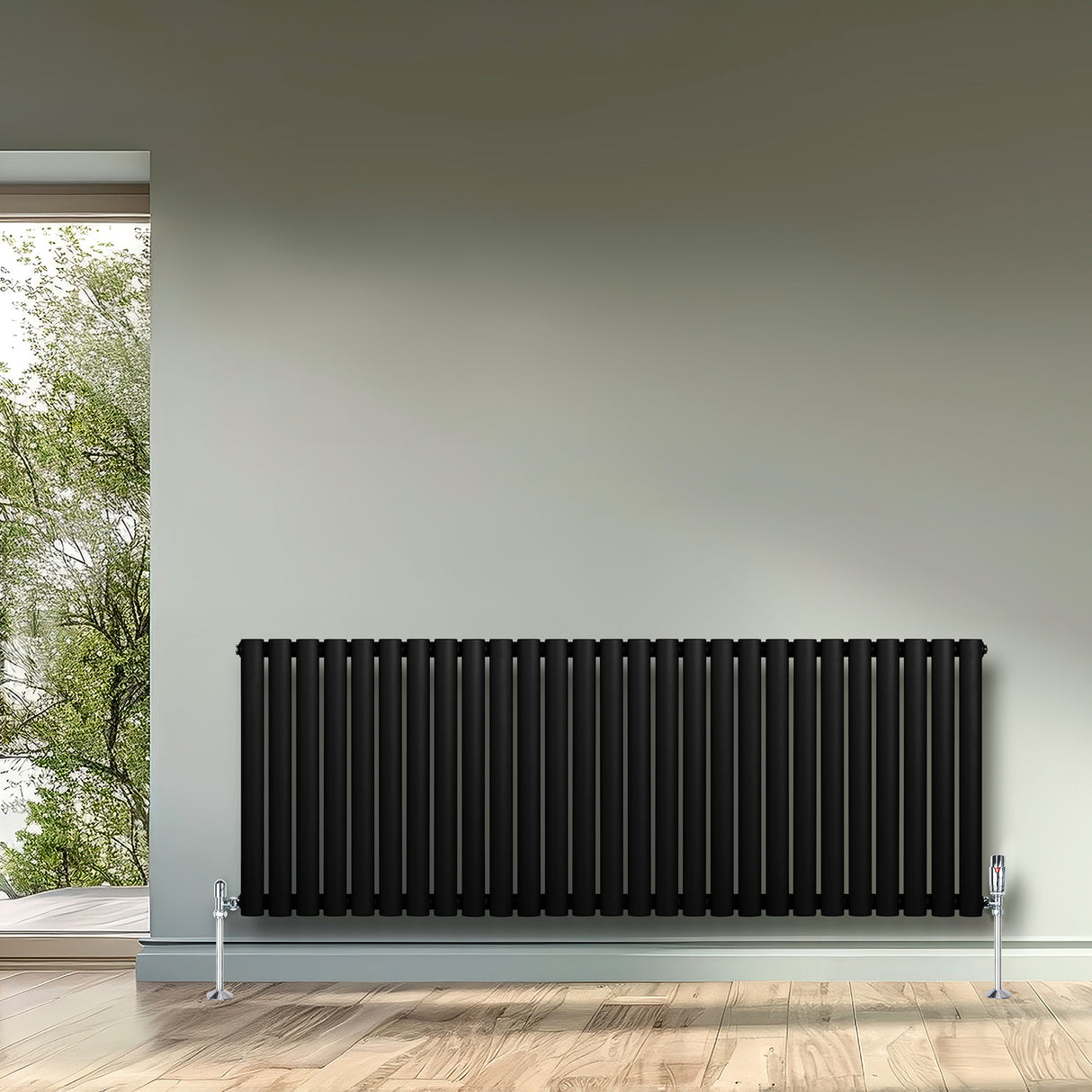 Ovale zwarte design radiator met één kolom, 600 mm x 1620 mm, geplaatst tegen een lichte muur met een houten vloer en raam uitzicht op groen