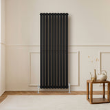Ovale zwarte design radiator van 1600 mm x 600 mm met een moderne, strakke uitstraling en verticale kolommen in een lichte kamer