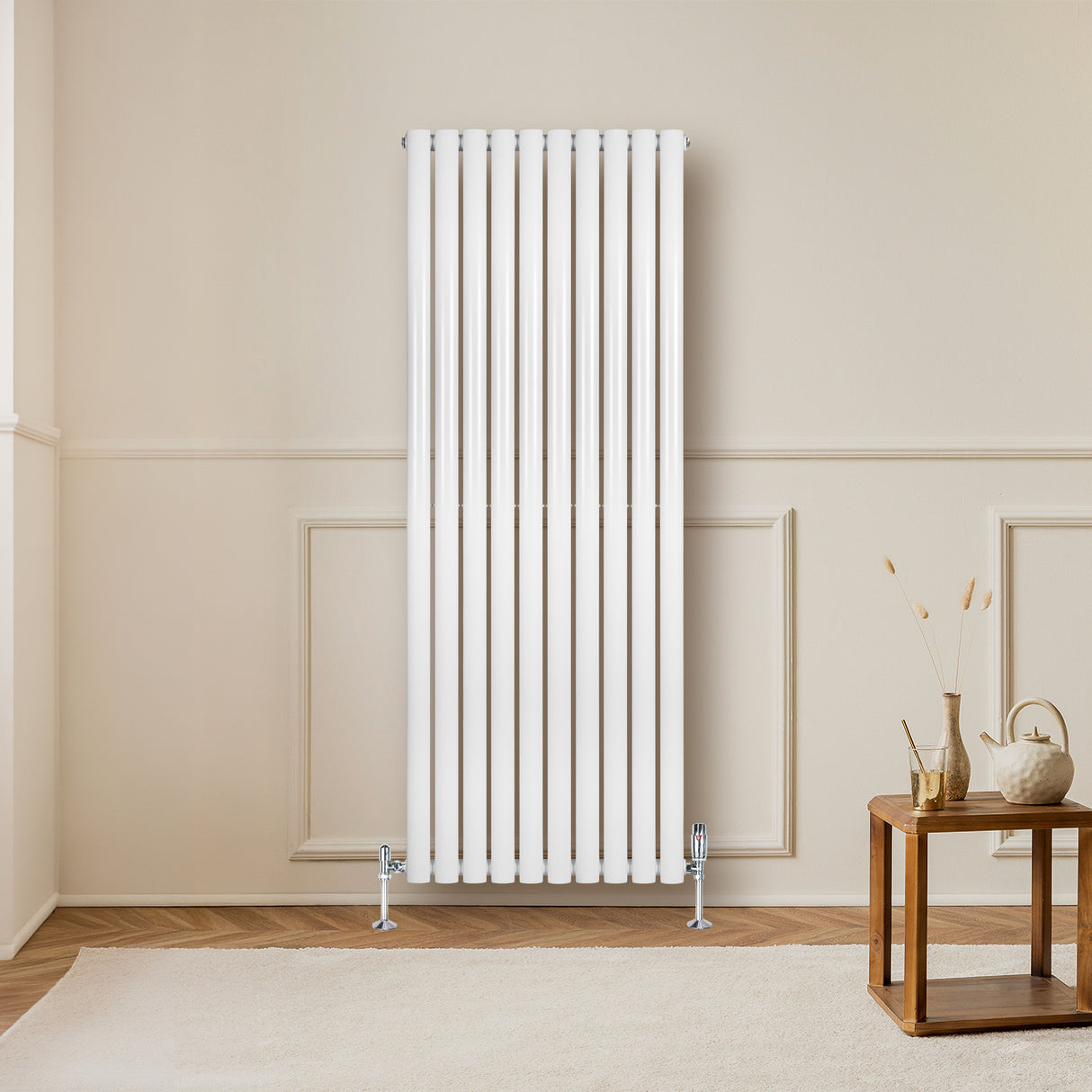 Ovale witte designradiator met één kolom, 1600 mm x 600 mm, geplaatst tegen een lichte muur met houten vloer en een houten tafel