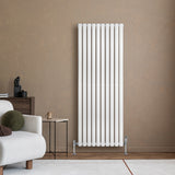 Ovale witte designradiator met één kolom, 1600 mm x 600 mm, geplaatst tegen een warme, neutrale muur in een moderne woonkamer