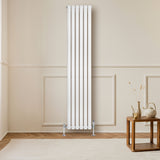 Ovale design radiator in wit met één kolom, 1800 mm x 360 mm, geplaatst tegen een lichte muur, naast een houten salontafel
