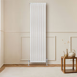 Ovale witte design radiator met één kolom, 1800 mm x 480 mm, geplaatst tegen een lichte muur in een moderne woonkamer