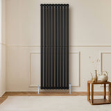 Ovale zwarte designradiator van 1800 mm x 600 mm met een moderne, strakke uitstraling en verticale kolommen in een lichte kamer