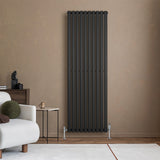 Ovale zwarte designradiator met één kolom, 1800 mm x 600 mm, geplaatst tegen een neutrale muur in een moderne woonkamer