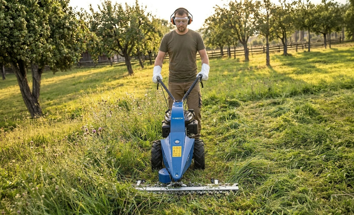 Een man in een groen shirt en veiligheidsbril maait gras met een blauwe grasmaaier in een boomgaard met groene bomen
