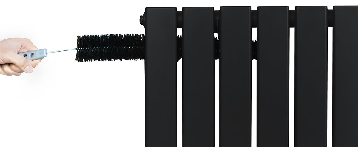Zwarte radiator met een hand die een schoonmaakborstel vasthoudt, ideaal voor het verwijderen van stof en vuil tussen de lamellen