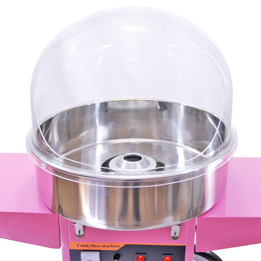 Roze suikerspinmachine met een glanzende roestvrijstalen kom en een doorzichtige beschermkap, ideaal voor feesten en evenementen